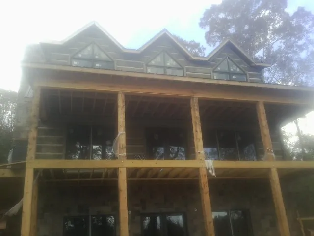 Dormers and porch framing on a large log home under construction — Roof Coating work by our crew in Baldwyn