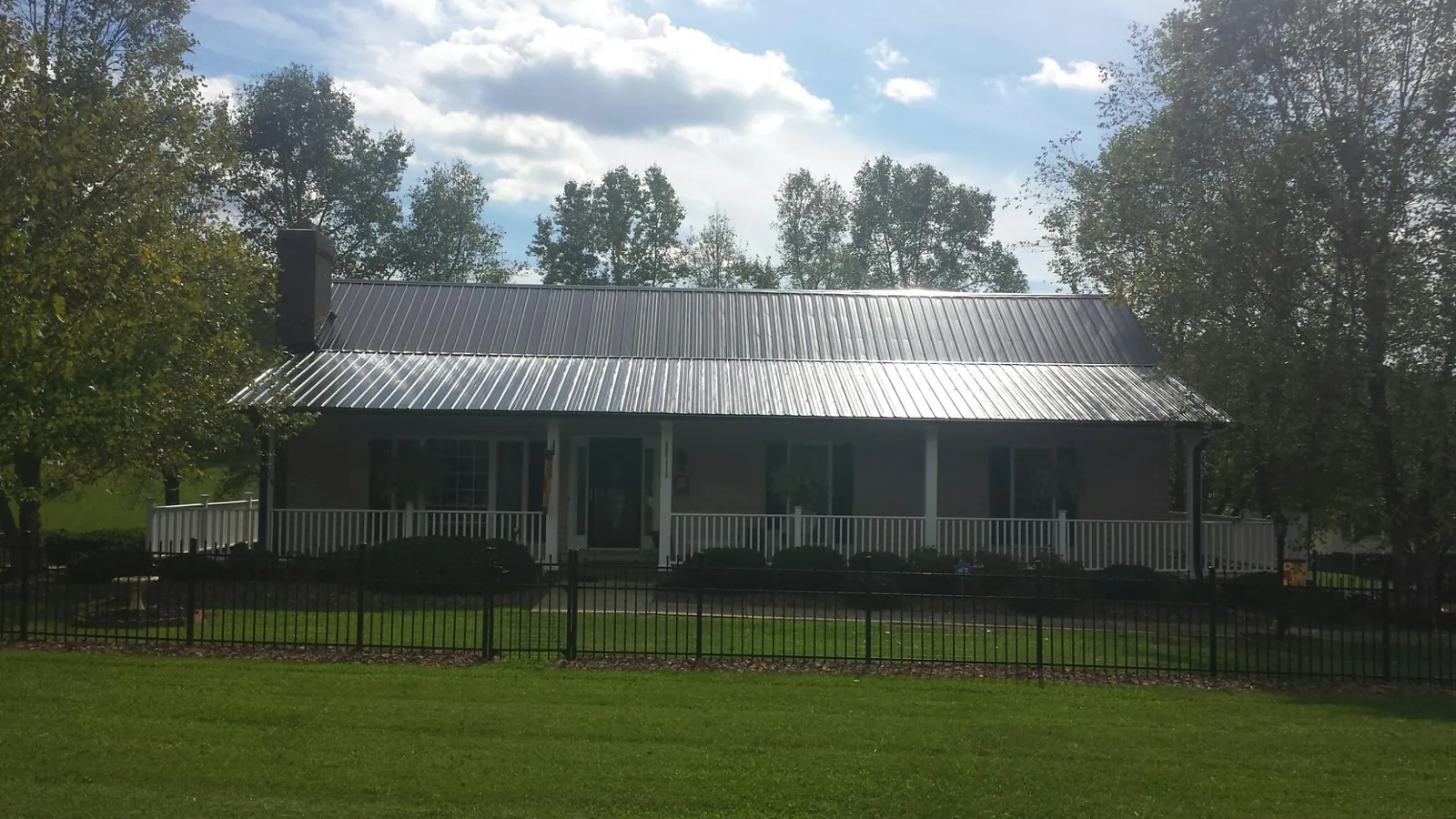 Gray metal roof on a brick ranch with a full width front porch — Gutter Guard Installation work by our crew in Baldwyn