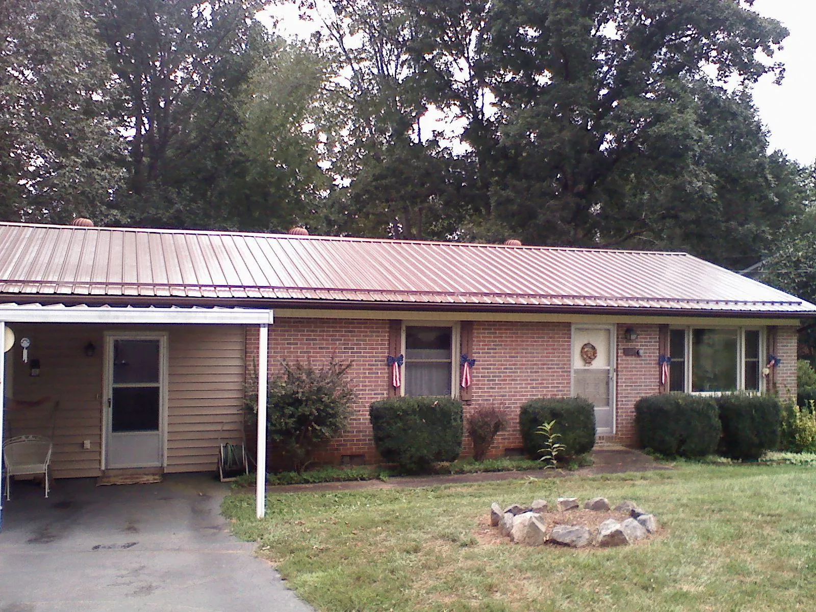 Bronze metal roof and carport on a brick ranch home — Roof Repair work by our crew in Baldwyn